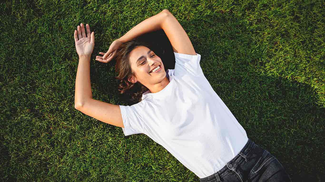 Femme allongée dans l'herbe, détendue et heureuse. 
